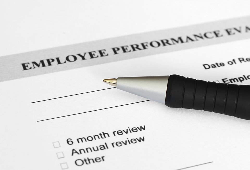 A picture of a pen laying on top of an employee review sheet