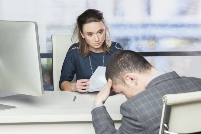 A woman at her desk talking to an employee from her HR team.