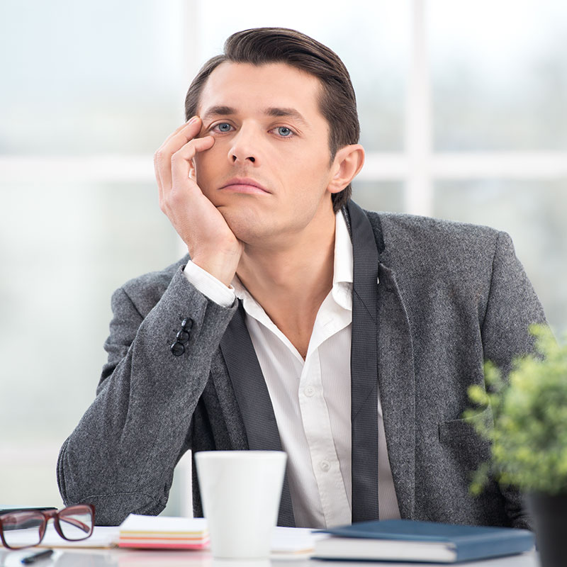 photo of young businessman sitting at his desk looking very bored