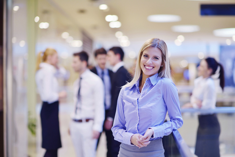 business woman with her staff in background at office