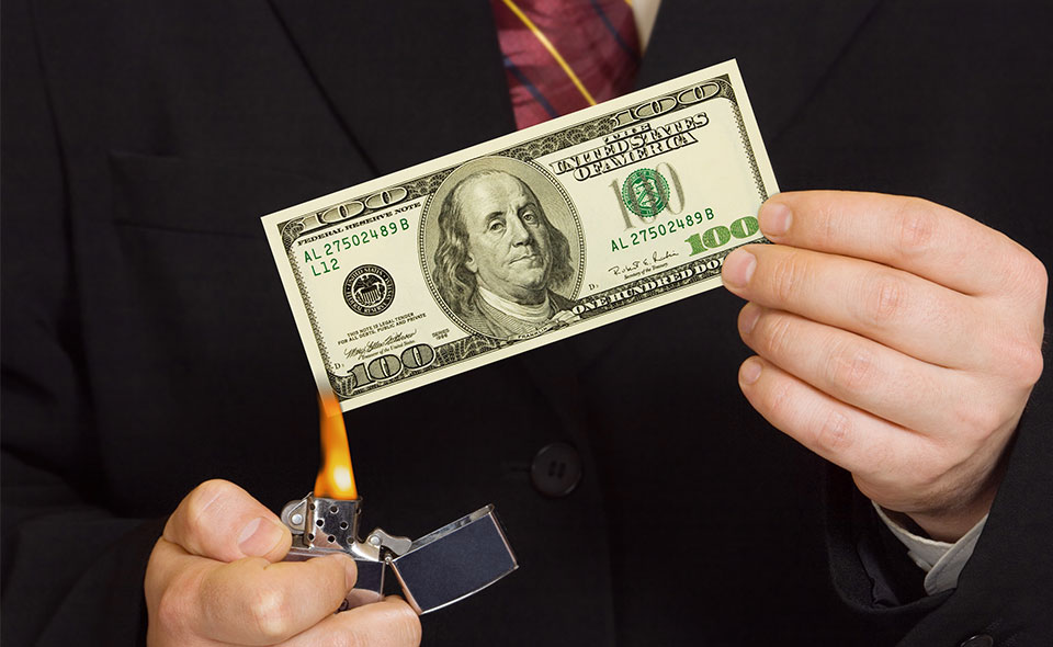 A picture of a person preparing to burn a $100 bill.