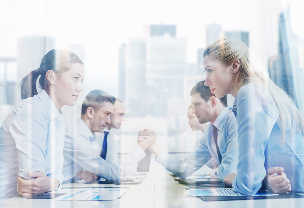 photo of businesspeople intensely starting at each other across a conference room table