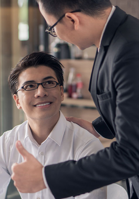 setting-an-example photo of professional manager giving a smiling employee a thumbs up for a job well done