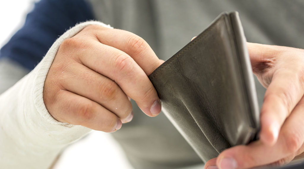 photo of injured worker with cast opening up his wallet looking for money